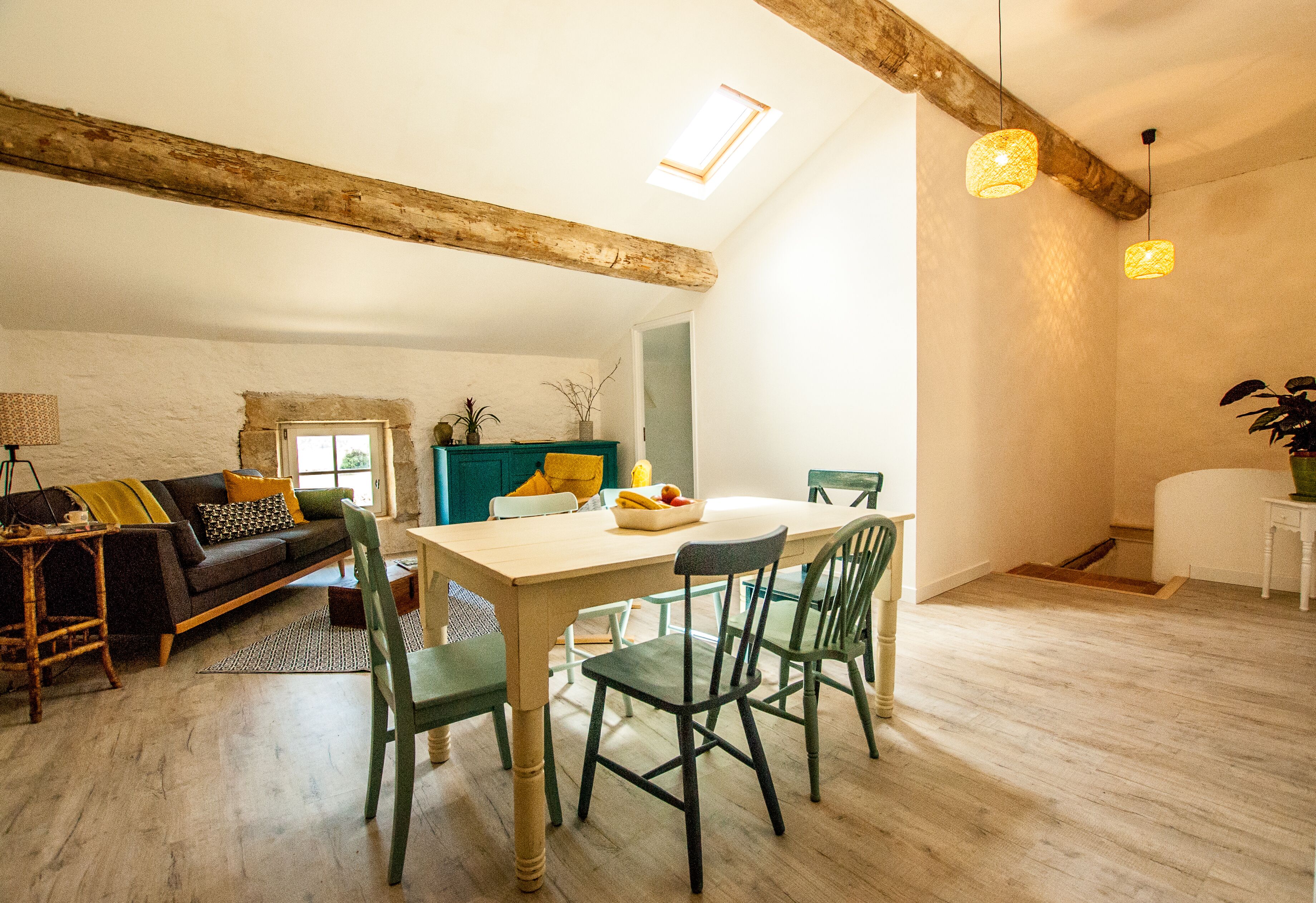 A dining area with a wooden table, green chairs, and a white ceiling beam.