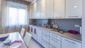 Une cuisine moderne avec des meubles blancs, un évier et un coin repas comprenant une table et des chaises.
