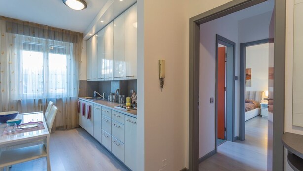 Une cuisine moderne avec des meubles blancs, une table à manger avec des chaises et un îlot de cuisine.