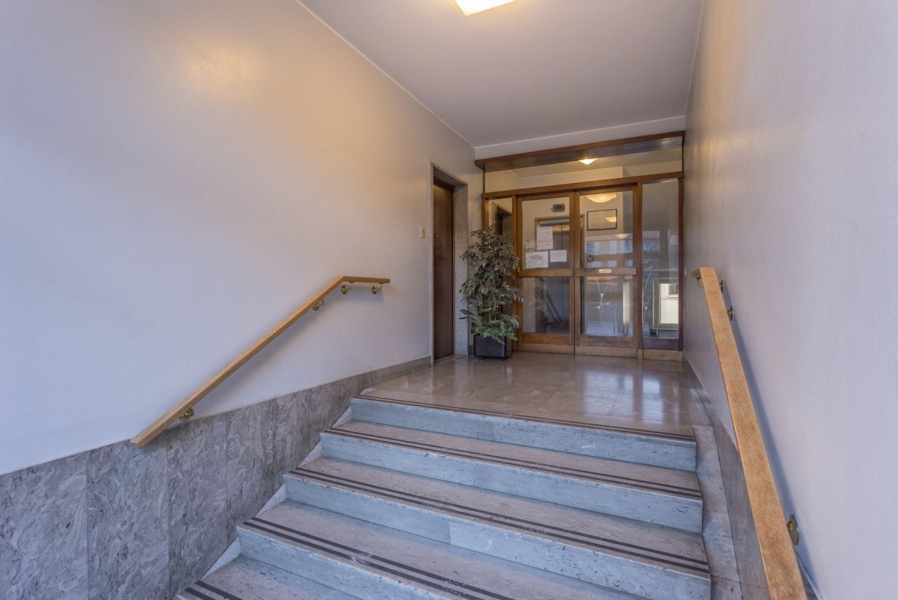 Eine Treppe mit Handlauf, einem Blumentopf und einer Tür zu einem Innenraum.