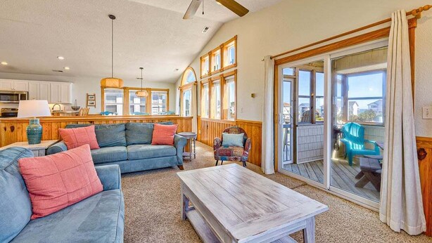 A spacious living area with a blue sofa, a wooden coffee table, and a ceiling fan.