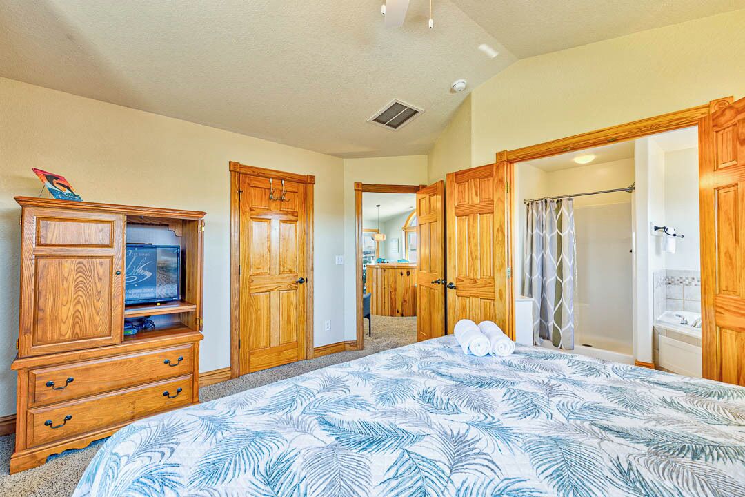 Une chambre à coucher avec un grand lit, une armoire en bois et un téléviseur posé sur une commode.