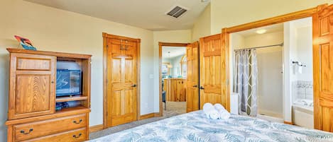 Une chambre à coucher avec un grand lit, une armoire en bois et un téléviseur posé sur une commode.