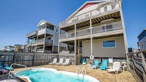 A two-story building with a pool area, including a hot tub and lounge chairs.