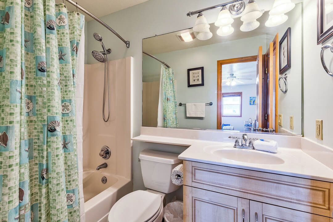 A bathroom with a bathtub, toilet, sink, and a large mirror.