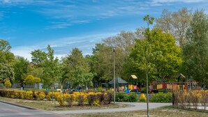 Un parque con juegos infantiles, un pabellón y una cama de flores bien cuidada.