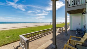 A beach view from a covered porch with a railing, a door, and two chairs. - Beachfront Escape | Ocean Views, Heated Pool & Hot Tub (Corpus Christi)