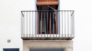 Un bâtiment à deux étages doté d’un balcon, de deux portes en bois et d’une petite fenêtre.