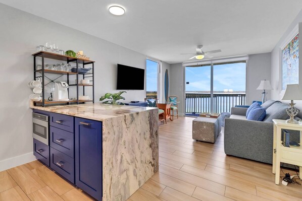 A modern kitchen with a marble island, built-in appliances, and a dining area with a view of the sea.