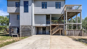 A two-story house with a front porch, a wooden deck, and a staircase leading to an upper level. - Even Steven | 570 ft from the beach | Private Pool | Duck (Duck)