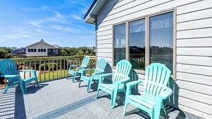 A deck with turquoise Adirondack chairs and a view of a white building with large windows. - Even Steven | 570 ft from the beach | Private Pool | Duck (Duck)