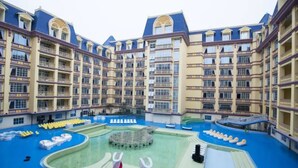 A hotel with multiple floors, balconies, and a central swimming pool area with lounge chairs and water slides. - Floloving Hotel (Guangzhou)