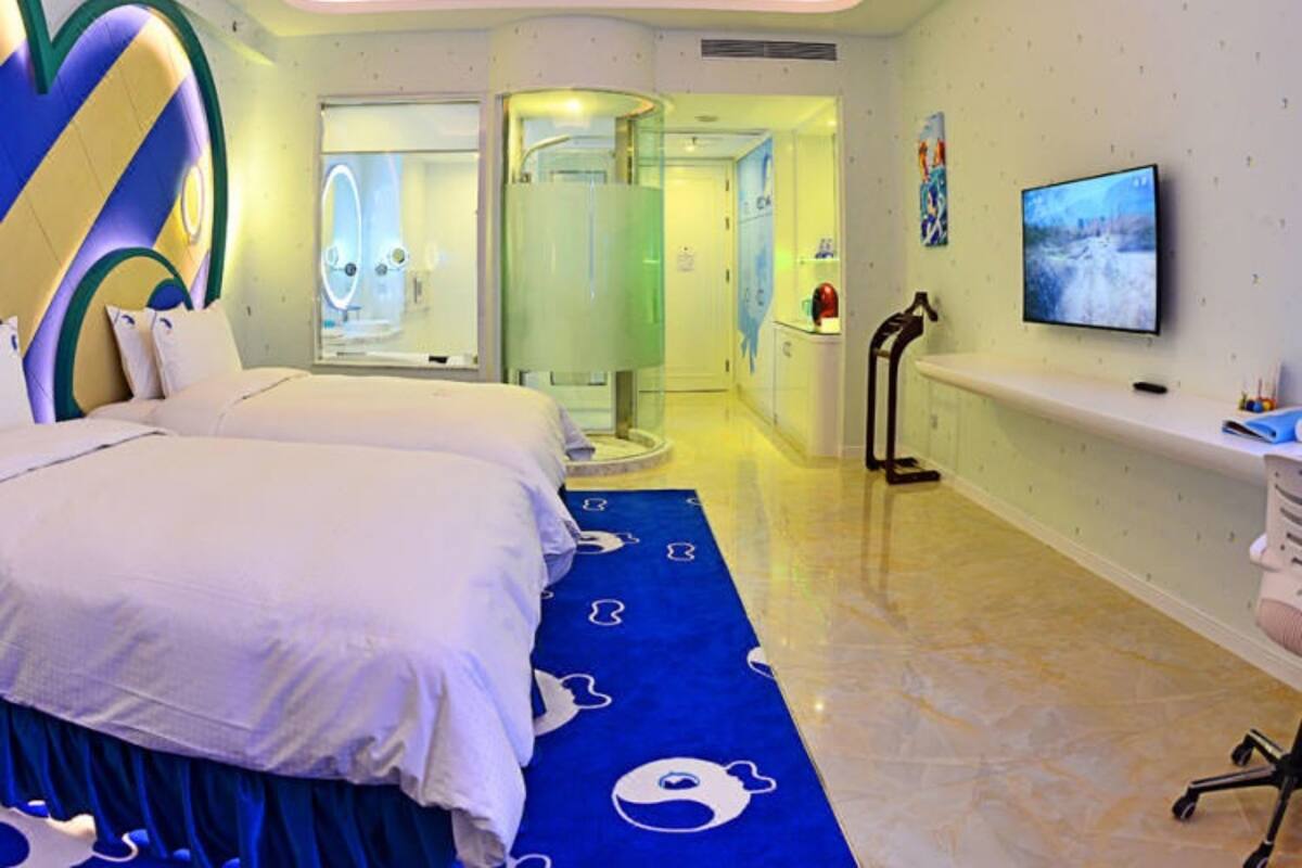 A modern hotel room with a large bed, a TV, and a bathroom visible through an open door.