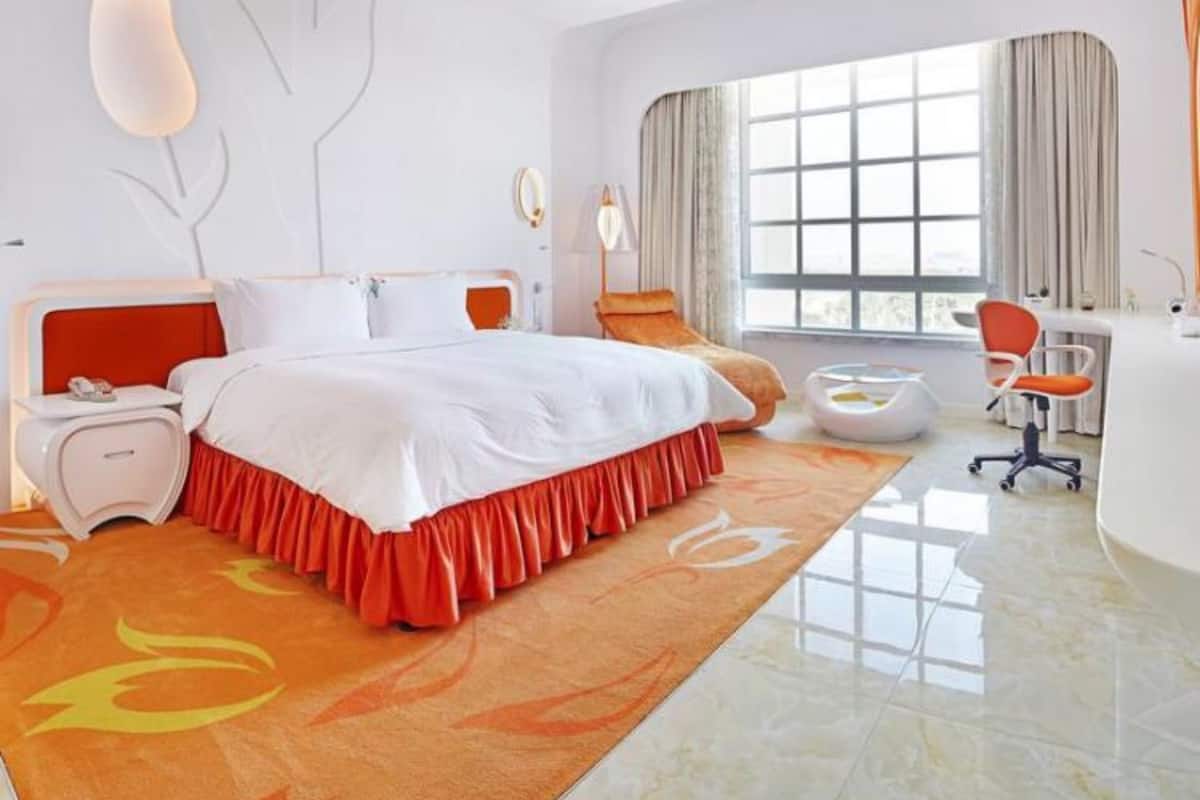A modern bedroom with a large bed, a desk, and a chair.