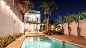 A pool area with a house, palm trees, and outdoor furniture. - 2BR · Steps to Malecón · Panoramic views ·  Private pool (Zona Central)