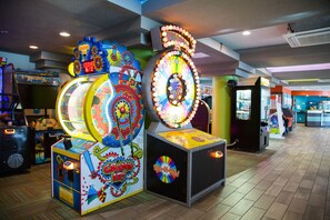 A brightly lit arcade with various gaming machines, including a spinning wheel game and a 'Big Buck' slot machine. - Gorgeous Direct Oceanfront King Efficiency + Official On-Site Rental Privileges (Myrtle Beach)