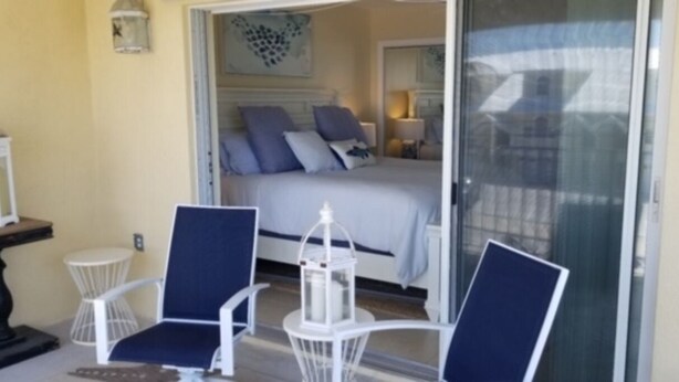 A bedroom with a bed, two chairs, a small table, and a window. - Key Colony Beach 3/3 Townhouse - Ocean View (Key Colony Beach)