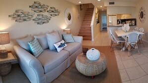A living room with a sofa, coffee table, and dining area with chairs. - Key Colony Beach 3/3 Townhouse - Ocean View (Key Colony Beach)