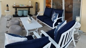 A patio area with white furniture, including a sofa and chairs, and a small table. There are decorative items like a lantern and a wall art piece. - Key Colony Beach 3/3 Townhouse - Ocean View (Key Colony Beach)