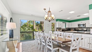 Una cocina amplia con armarios blancos, una isla central y una zona de comedor con sillas blancas.