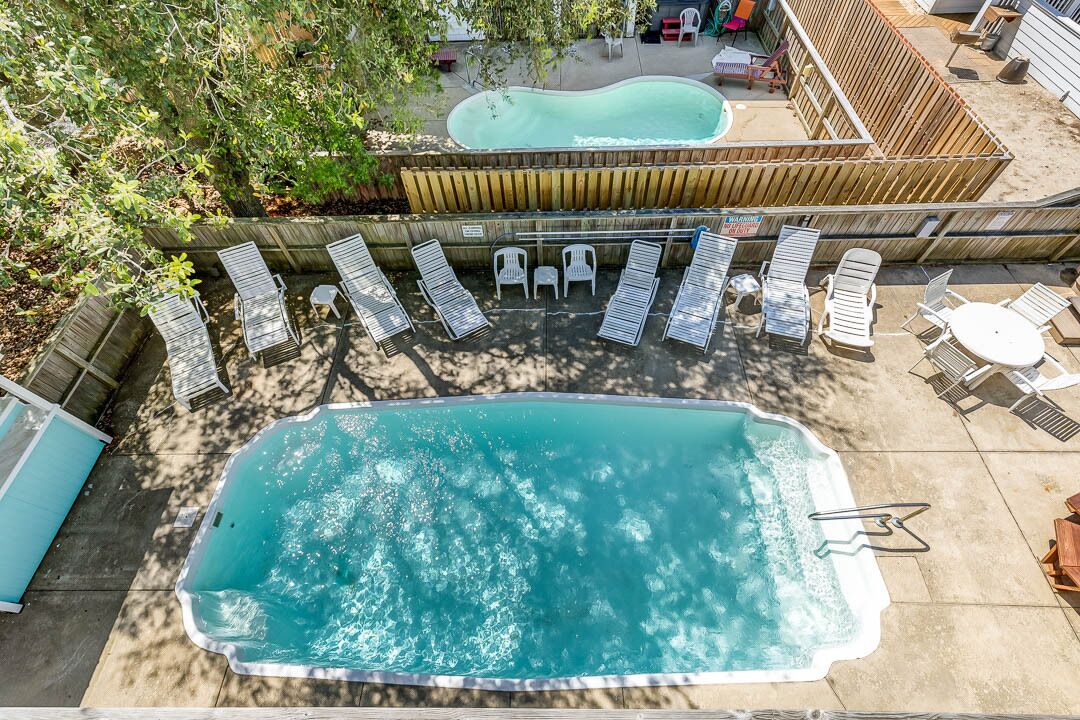A swimming pool with lounge chairs and a hot tub.