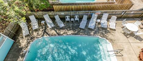 A swimming pool with lounge chairs and a hot tub.