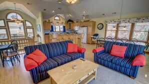 Ein geräumiges Wohnzimmer mit zwei gestreiften Sofas, einem Couchtisch und einem Essbereich mit Holzkästen.