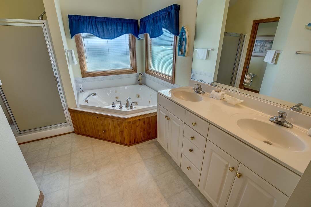 A bathroom with a double sink, a large bathtub, and a shower.