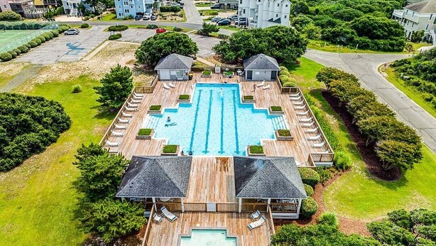 Ein Luftbild eines Resorts mit einem zentralen Schwimmbad, umgeben von Liegebereichen und zwei Gästehäusern.