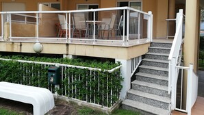 A building with a balcony, outdoor seating, and a staircase leading to an upper level. - PARQUEMAR VIII BL. II 1º SOLO FAMILIAS! (Xeraco Playa)