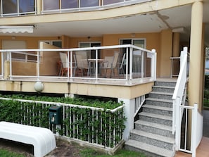 A building with a balcony, outdoor seating, and a staircase leading to an upper level.
