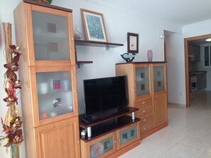A living room with a wooden entertainment unit, a flat-screen TV, and decorative items.