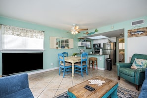 Relax in this spacious living area with a large flat-screen TV, comfortable seating, and a dining table.