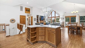 Uma cozinha espaçosa com armários de madeira, uma ilha grande e uma área de jantar com mesa e cadeiras.