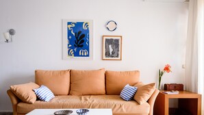 A living room with a beige sofa, a white coffee table, and a small wooden side table with a vase of flowers.