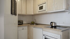 A kitchen with white cabinets, a microwave, a toaster, a sink, and a stove.