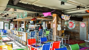 Un restaurante con sillas coloridas, una zona de bar y una pared de madera con un letrero de Sinclair.