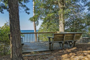 A wooden deck with a bench overlooking a body of water, surrounded by trees.