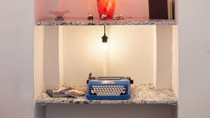 Un estante con una luz decorativa, una máquina de escribir y diversos objetos pequeños.