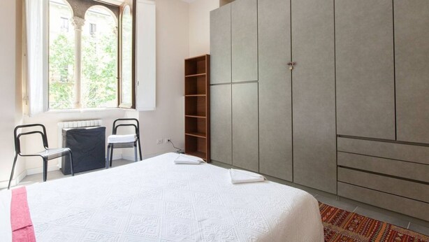 Une chambre à coucher avec un lit, une fenêtre, une armoire et un bureau.