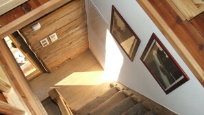 Una escalera de madera que lleva a una habitación con paredes blancas y cuadros enmarcados.