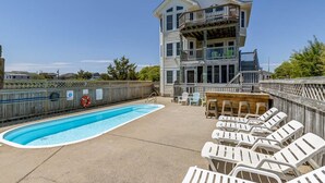 Uma área de piscina com espreguiçadeiras e um deck de madeira.