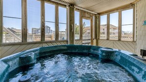 Uma banheira de hidromassagem em um quarto com janelas amplas, paredes de madeira e vista para as casas vizinhas.
