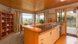 A kitchen with a large island, wooden cabinets, and a view of the outdoors. - Bullock Creek Chalet · Lake & mountain views (Wanaka)