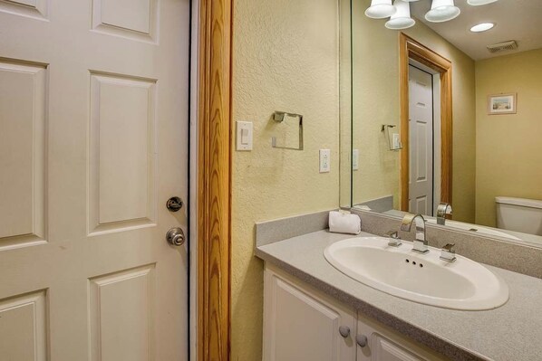 A bathroom with a white sink, a mirror, and a wooden door frame.