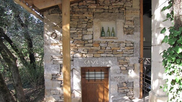 Un bâtiment en pierre avec une porte en bois et une étagère remplie de bouteilles.