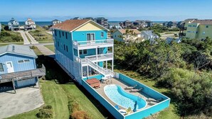 Una casa de dos pisos con una piscina grande y un balcón.
