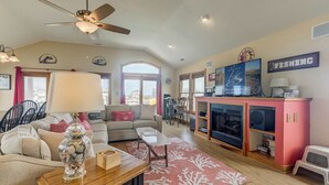 Una sala de estar amplia con ventilador de techo, chimenea y televisor.