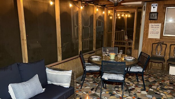 A cozy room with a dark blue sofa, a dining table set for four, and a mosaic tile floor.