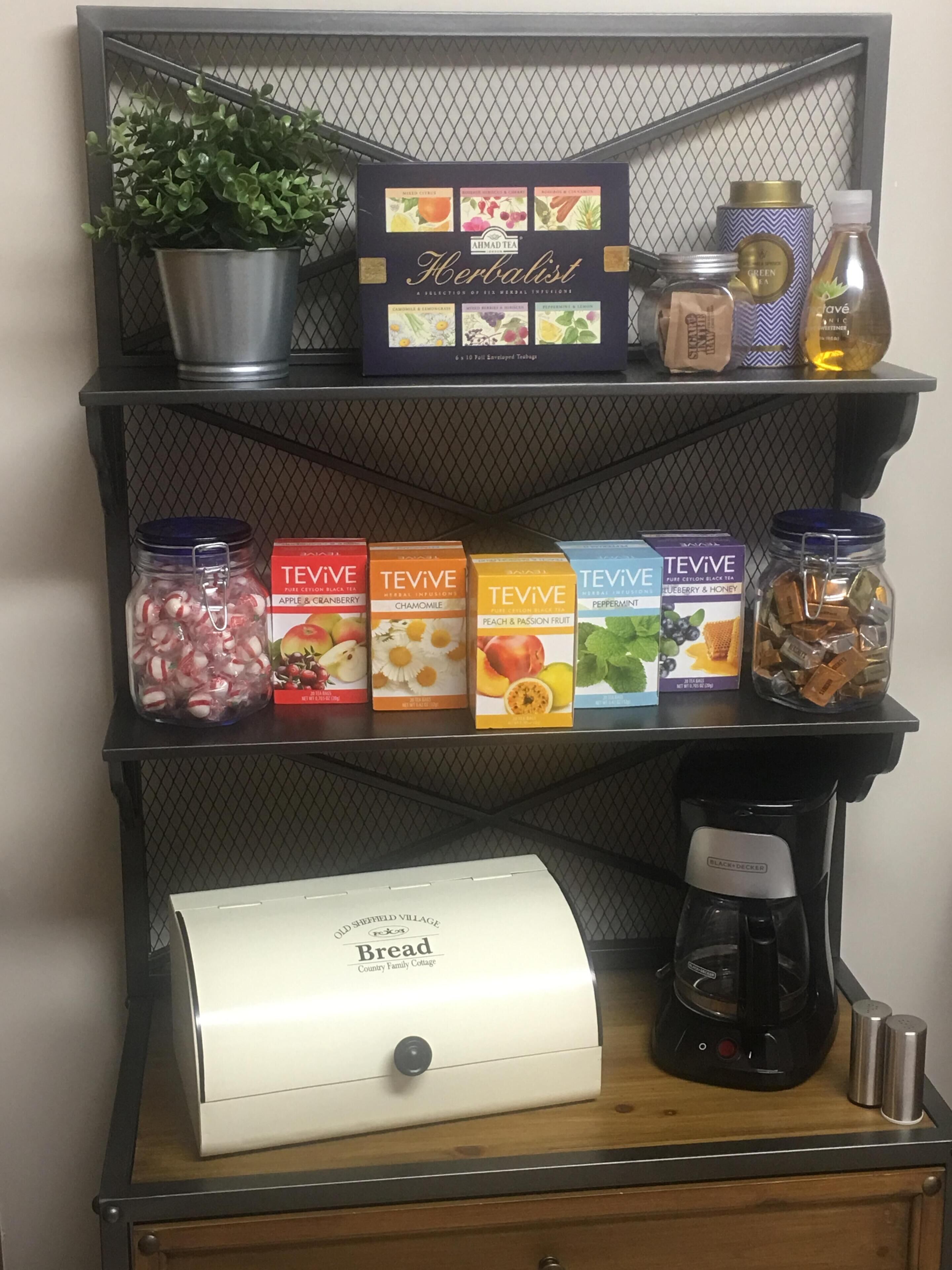 A kitchen counter with a coffee maker, a bread maker, and various tea boxes.